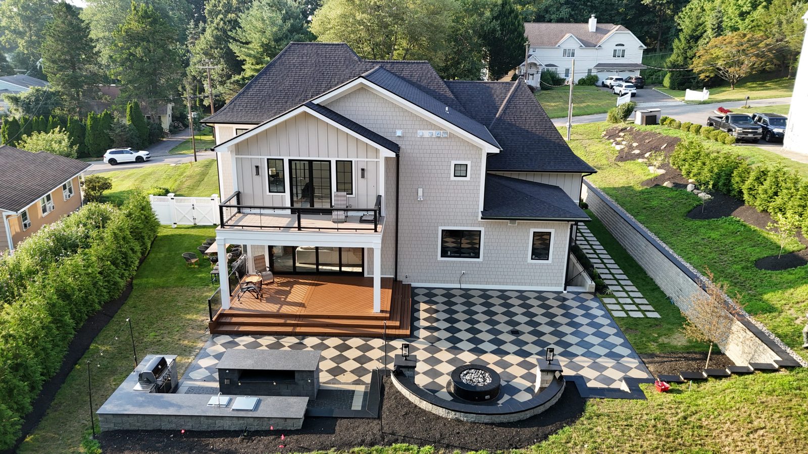 Unilock paver patio with fire pit and outdoor kitchen alongside a deck in the Hudson Valley