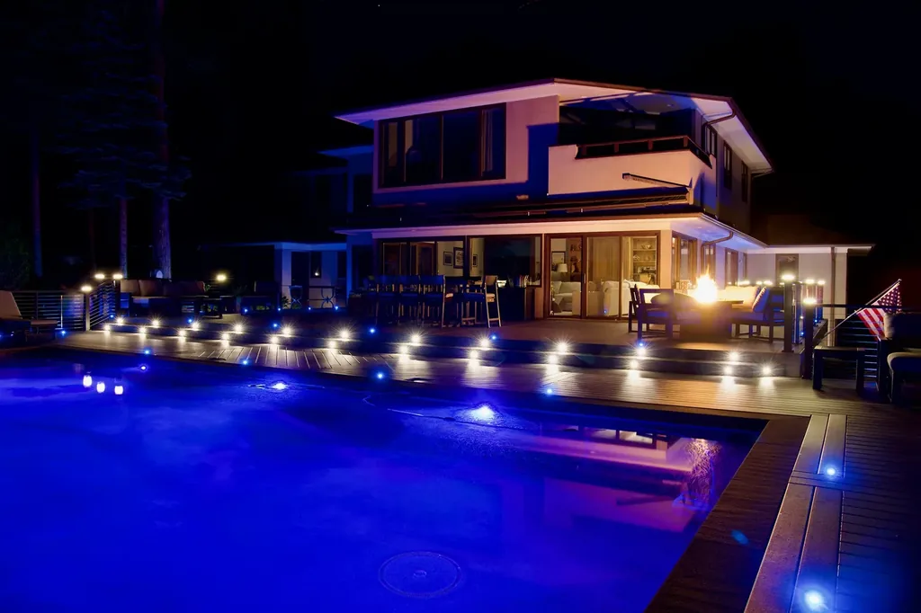 Multicolor LED deck lighting glowing around a night pool